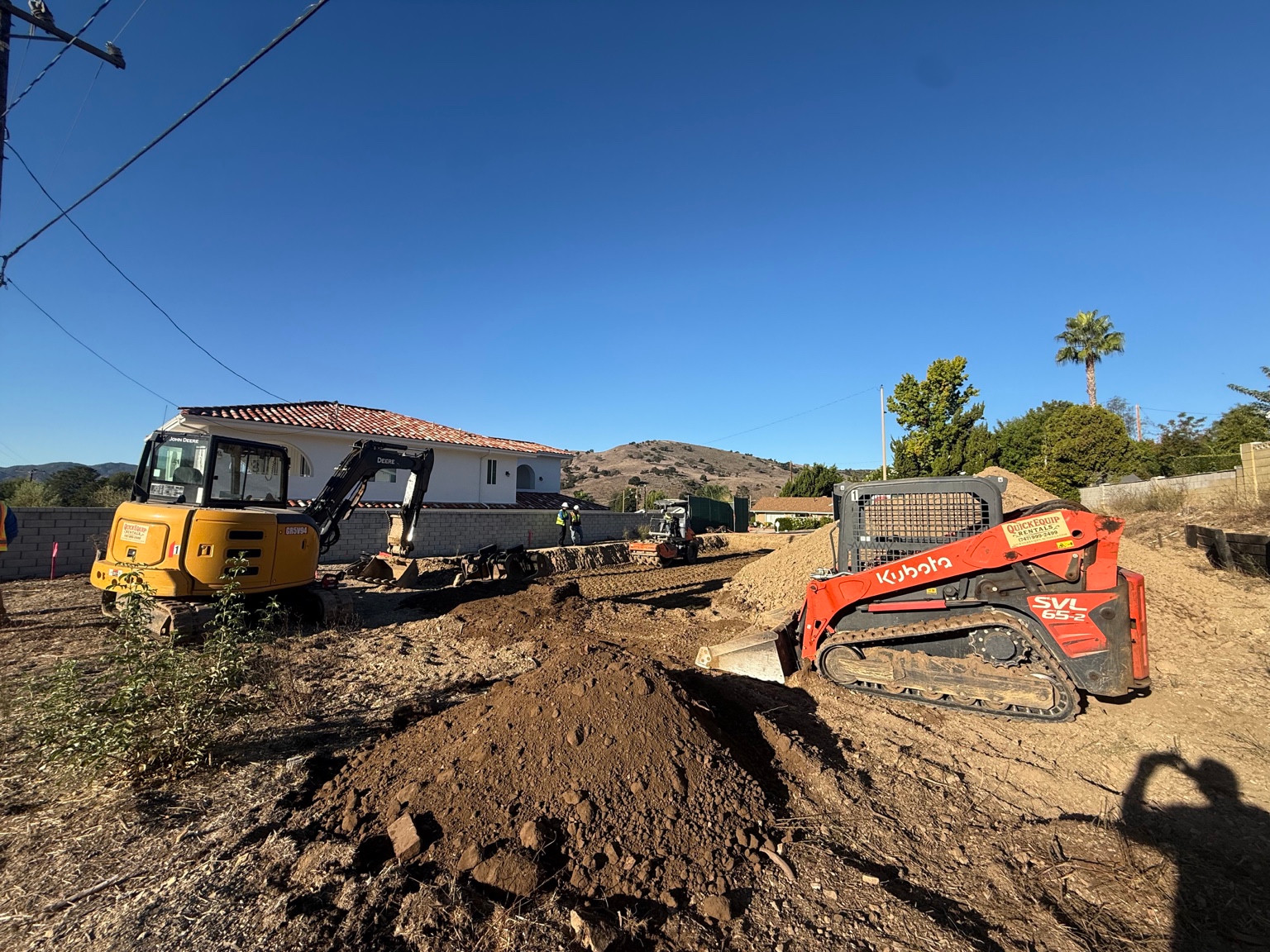 Excavator, track loader and workers at the DG Builders Calabasas construction site in daylight