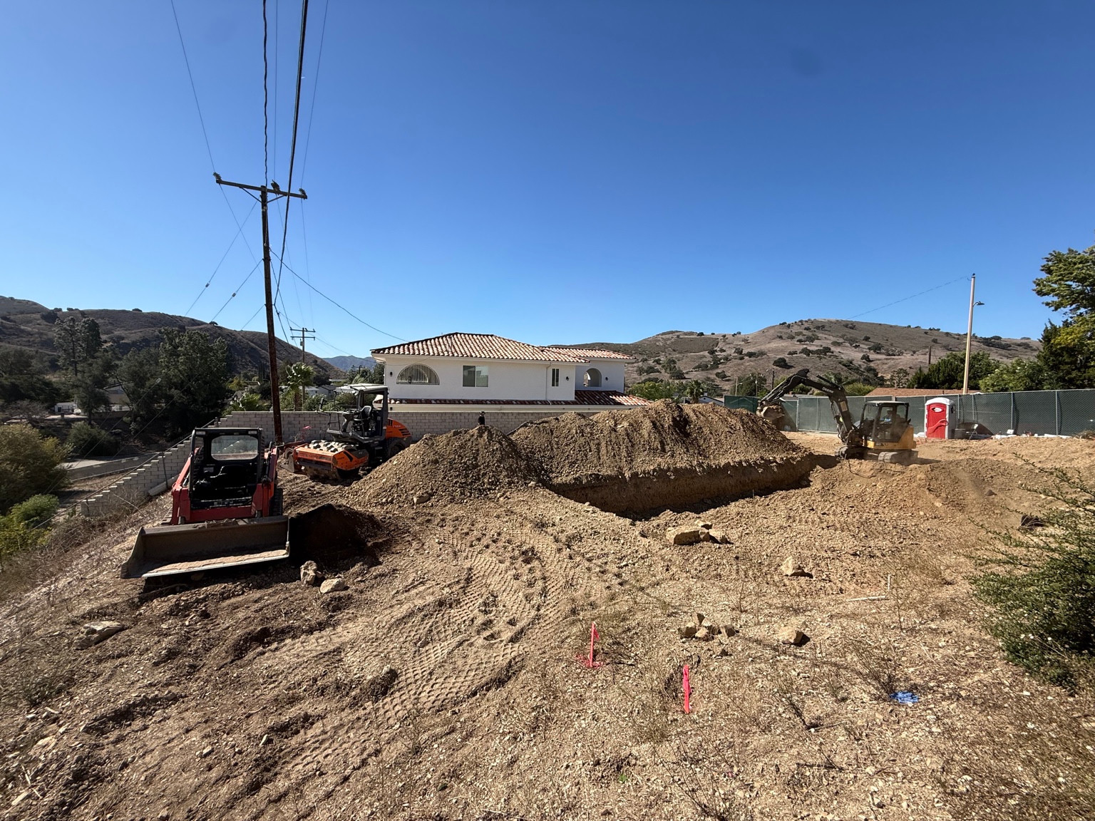 Excavator, loader and compactor around soil piles at the DG Builders Calabasas construction site
