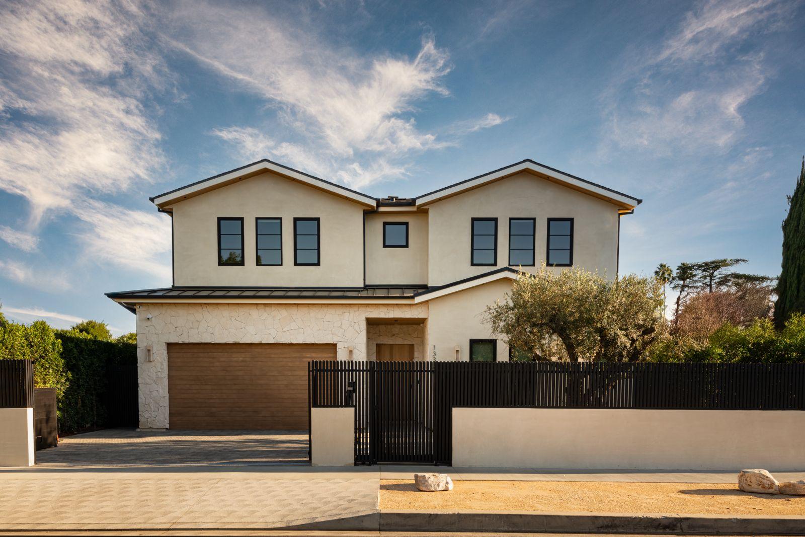 Two-story DG Builders home with light stucco, stone cladding and dark-framed windows